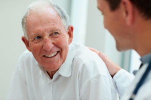 doctor patting back of smiling elderly patient